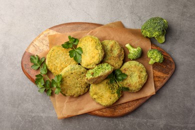 Delicious vegan cutlets with broccoli and parsley on light gray table, top view
