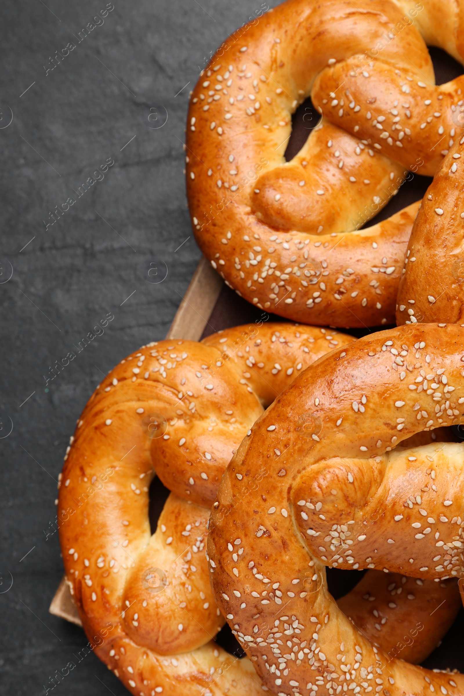 Photo of Delicious pretzels with sesame seeds on black table, closeup