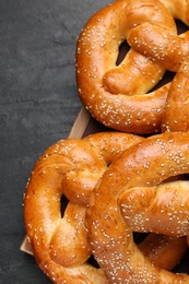 Delicious pretzels with sesame seeds on black table, closeup