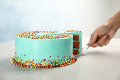 Woman taking slice of fresh delicious birthday cake at table, closeup