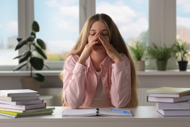 Young tired woman studying at white table indoors