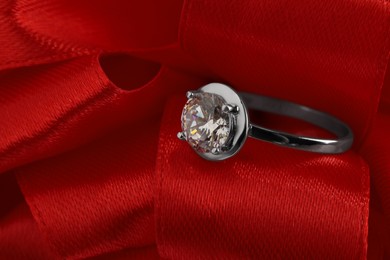 Photo of Beautiful red bow and engagement ring, closeup view
