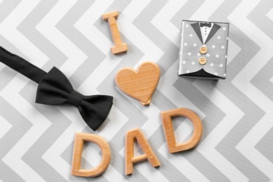 Photo of Phrase "I love dad", bow tie and gift box on color background. Father's day celebration