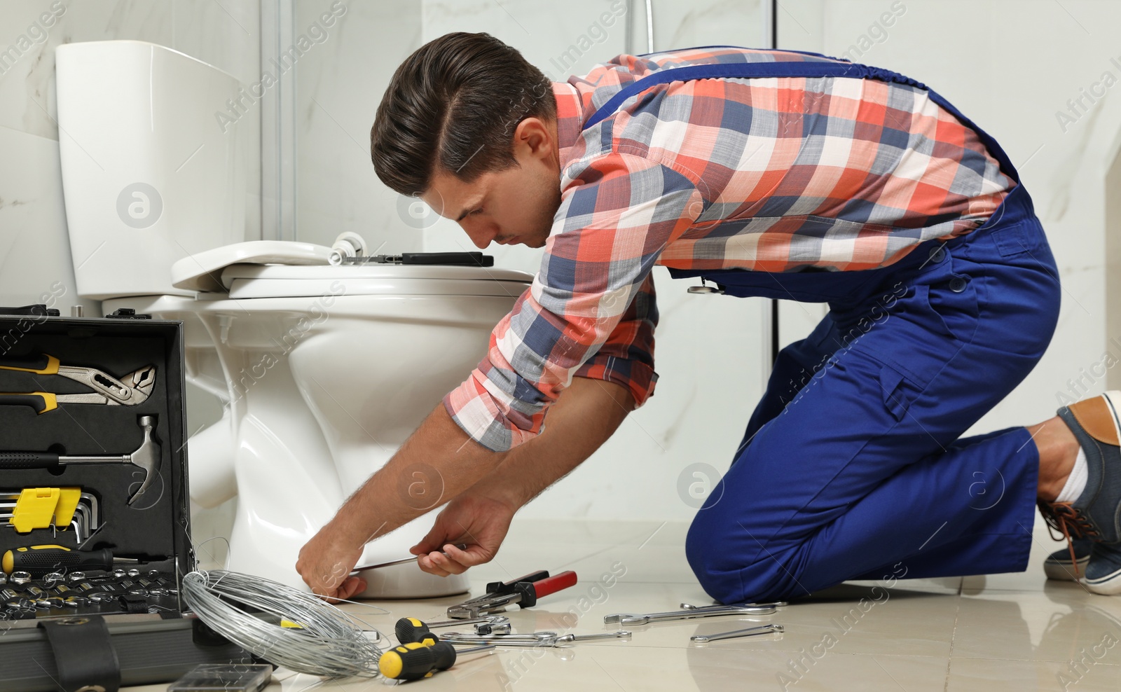 Photo of Professional plumber working with toilet bowl in bathroom