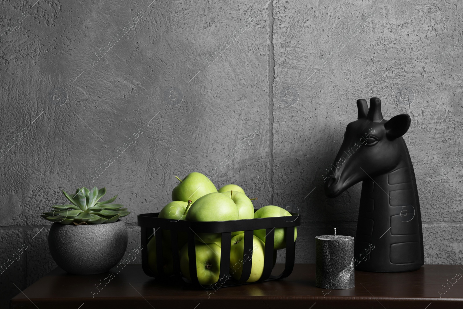 Photo of Wooden shelf with potted plant, decorative figure of giraffe and apples against grey wall, space for text