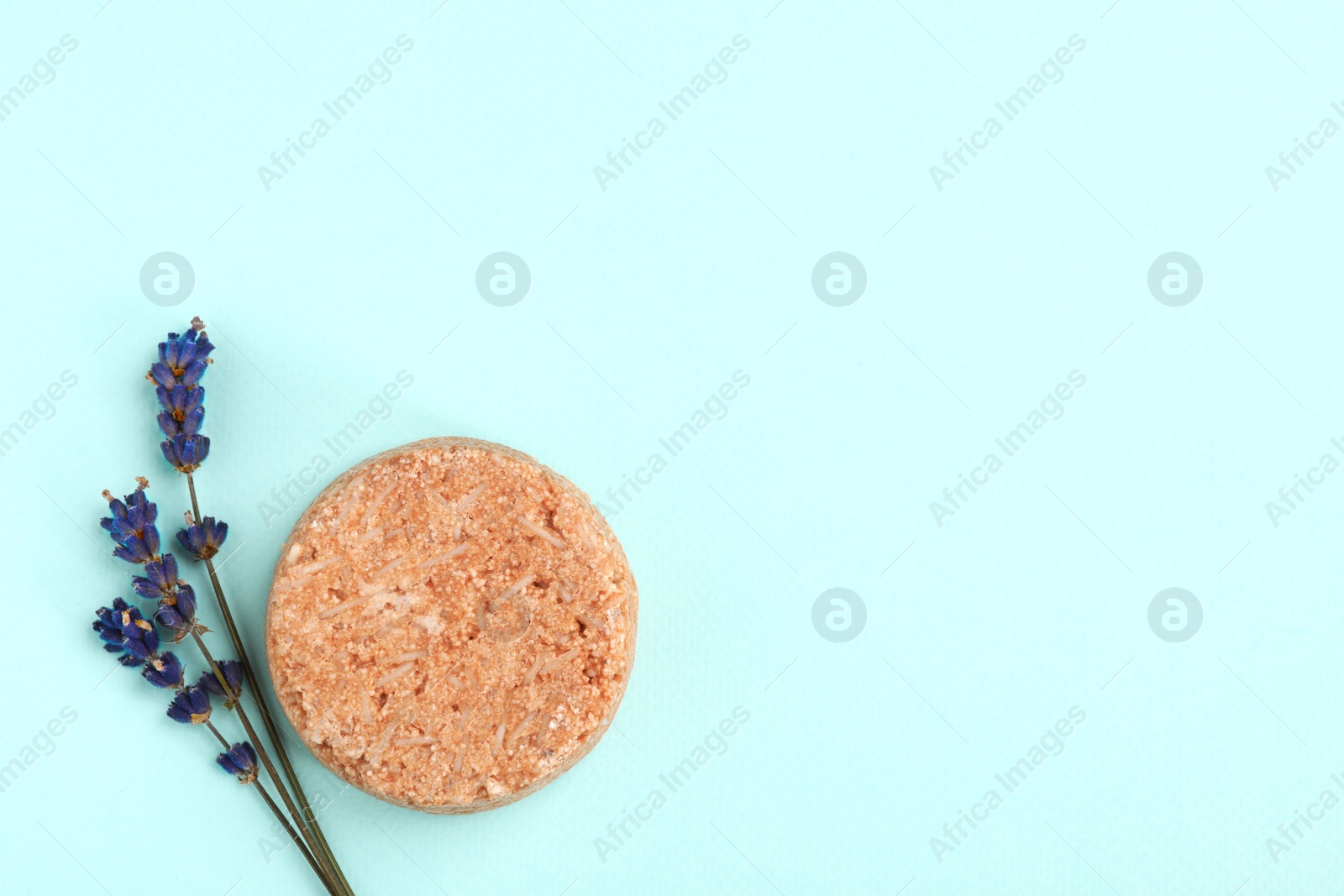 Photo of Solid shampoo bar and lavender on turquoise background, flat lay. Space for text