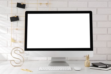 Photo of Office workplace with computer, stationery and decor on light table near white brick wall