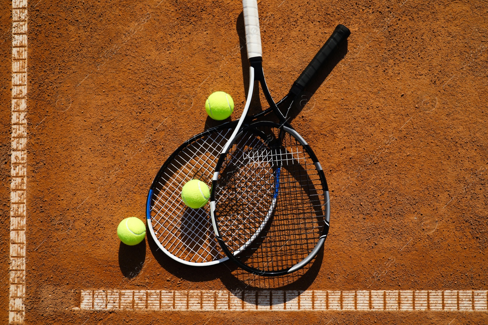 Photo of Tennis balls and rackets on clay court, flat lay