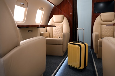 Image of Airplane cabin with yellow suitcase. Air travel