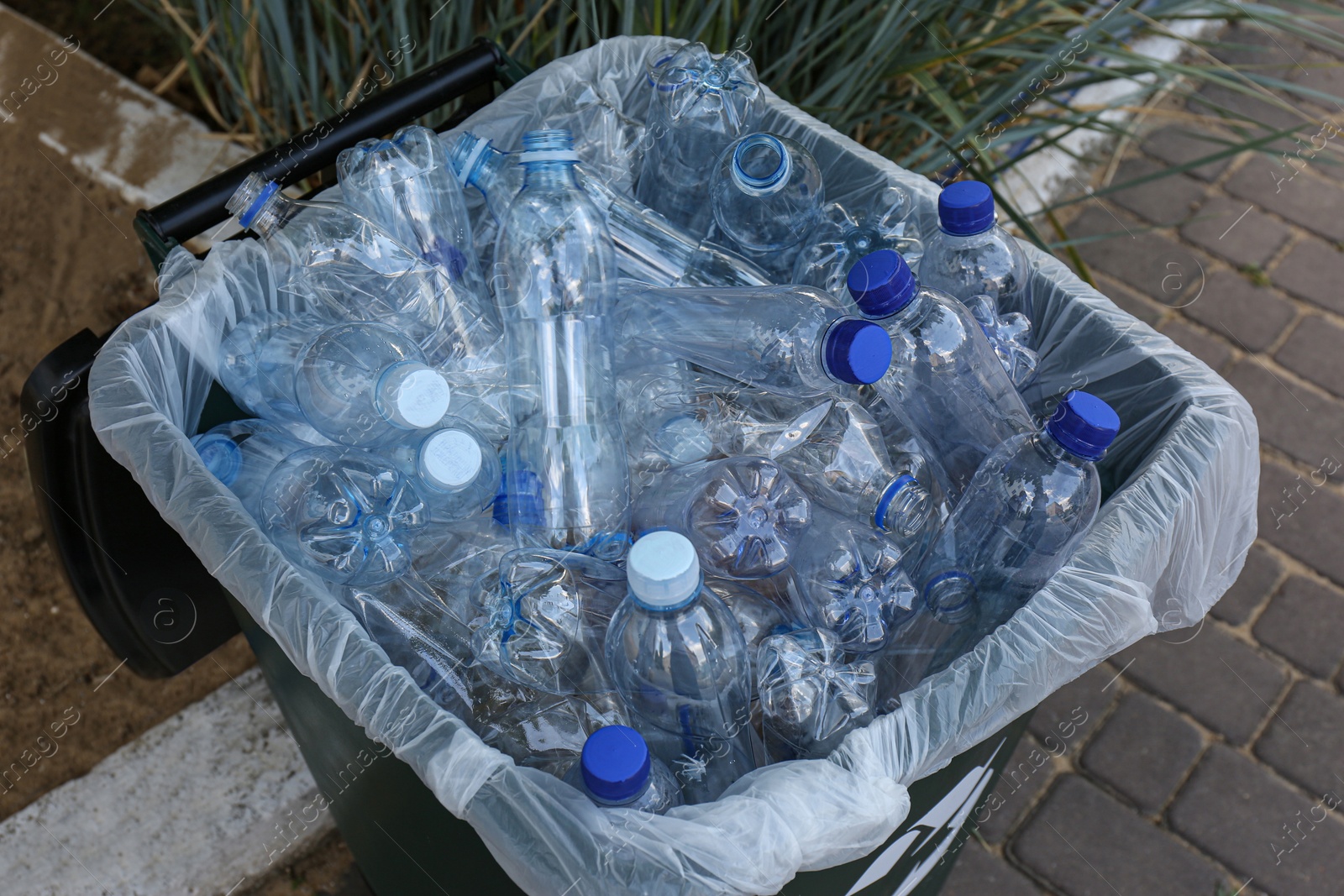 Photo of Many used plastic bottles in trash bin outdoors. Recycling problem