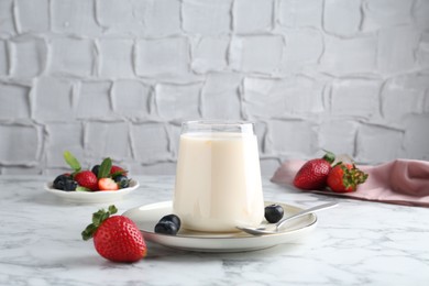 Photo of Tasty yogurt in glass and berries on white marble table