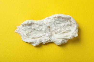 Photo of Smear of delicious cream cheese on yellow background, top view