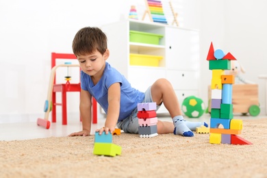 Cute little boy playing with colorful blocks on floor at home. Educational toy