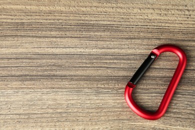 Photo of One metal carabiner on wooden table, top view. Space for text