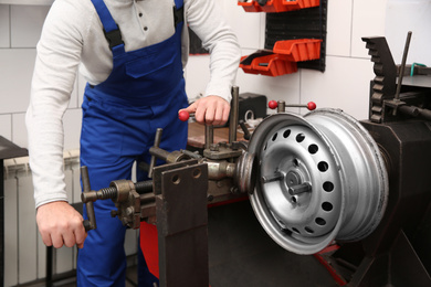 Photo of Mechanic working with car disk lathe machine at tire service, closeup