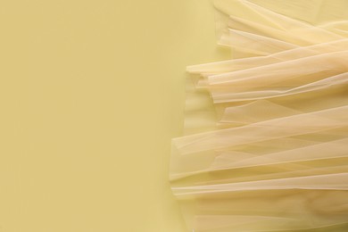 Photo of Beautiful tulle fabric on yellow background, top view. Space for text