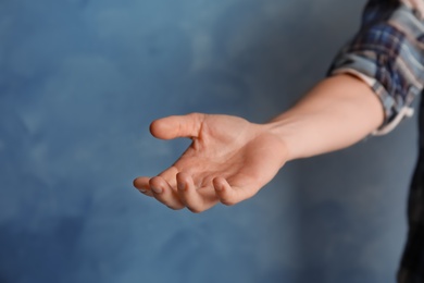 Woman offering helping hand on color background, closeup