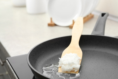 Frying pan with coconut oil on induction stove, closeup. Healthy cooking