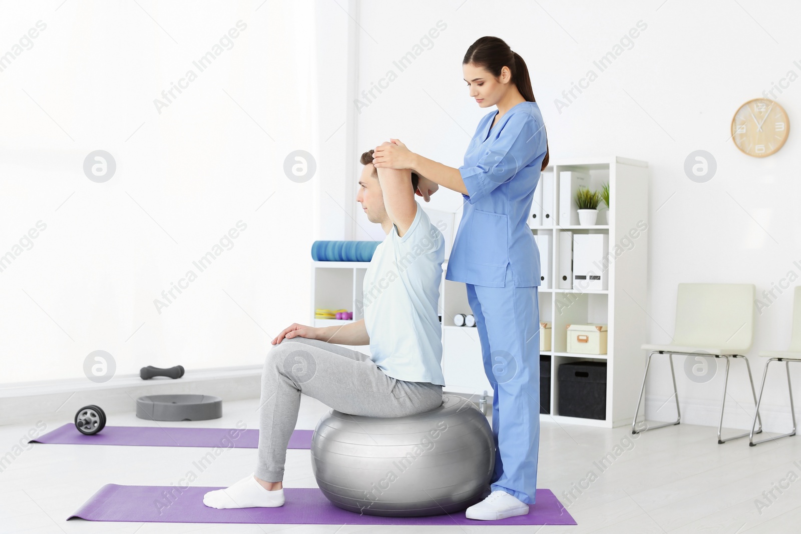 Photo of Physiotherapist working with young male patient in clinic