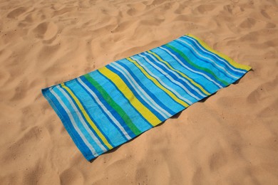 Photo of Soft bright striped beach towel on sand