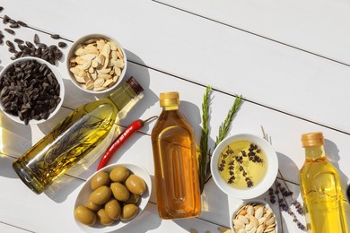 Photo of Different cooking oils and ingredients on white wooden table, flat lay. Space for text