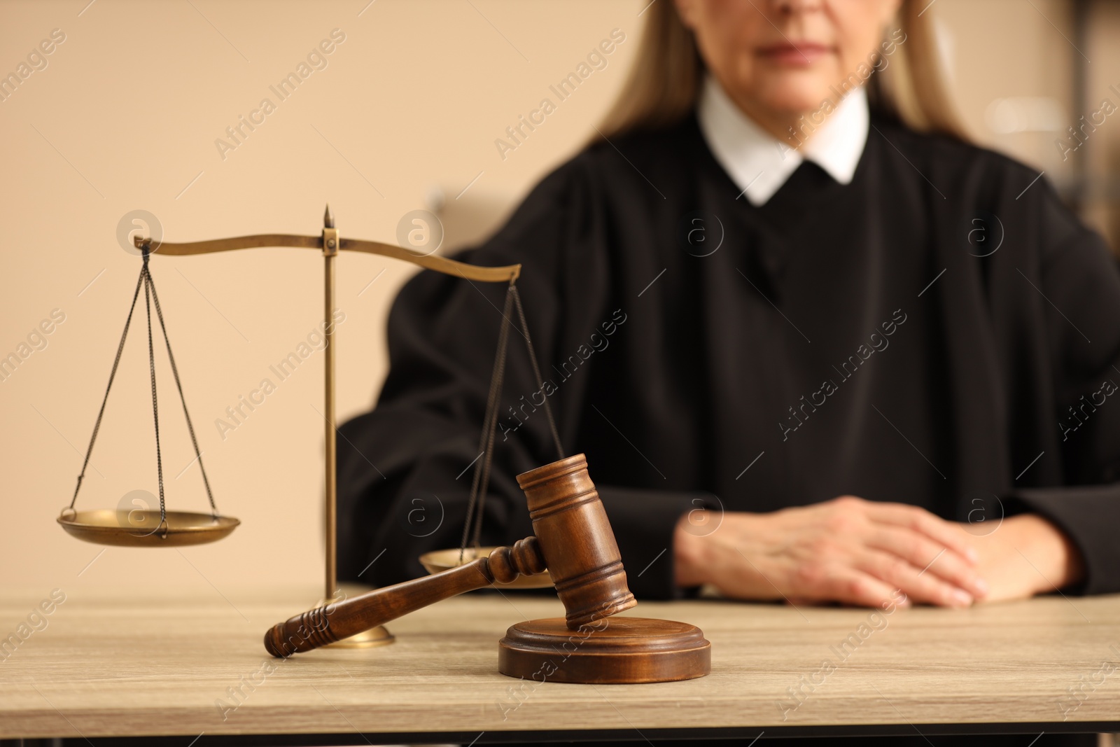 Photo of Judge working indoors, selective focus. Wooden mallet and scales on table