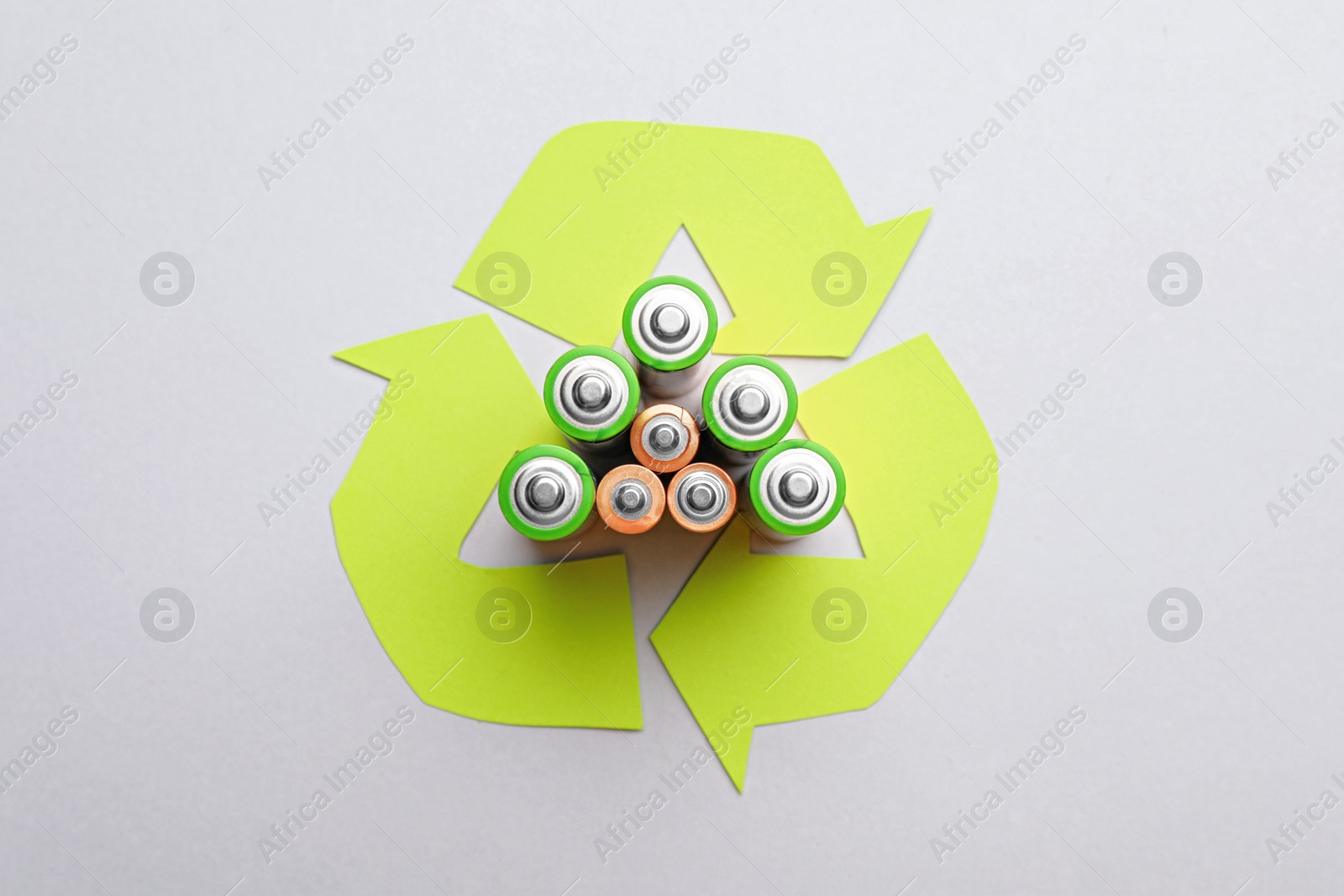 Photo of Used batteries and recycling symbol on white background, top view