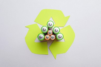 Photo of Used batteries and recycling symbol on white background, top view