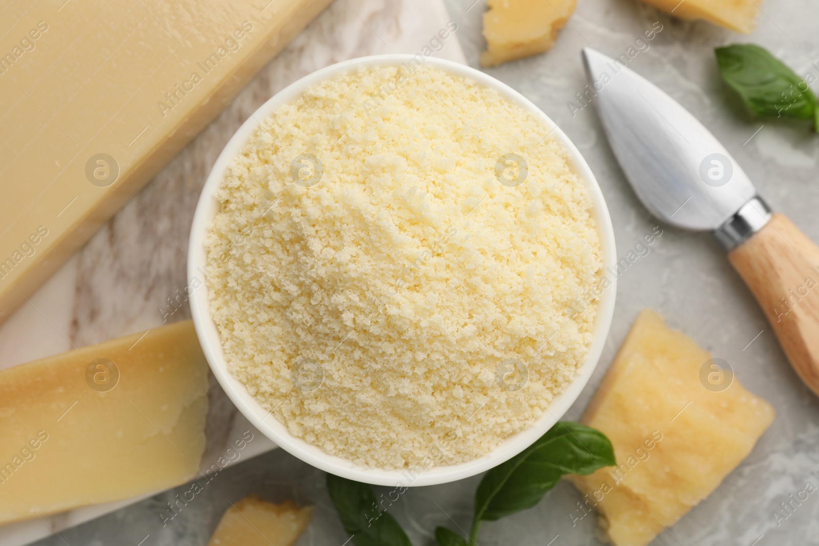 Photo of Flat lay composition with grated parmesan cheese, basil and knife on grey table