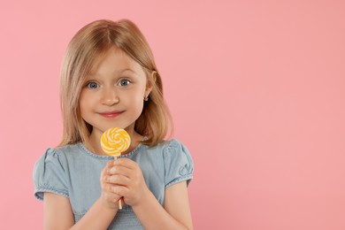 Portrait of cute girl with lollipop on pink background, space for text