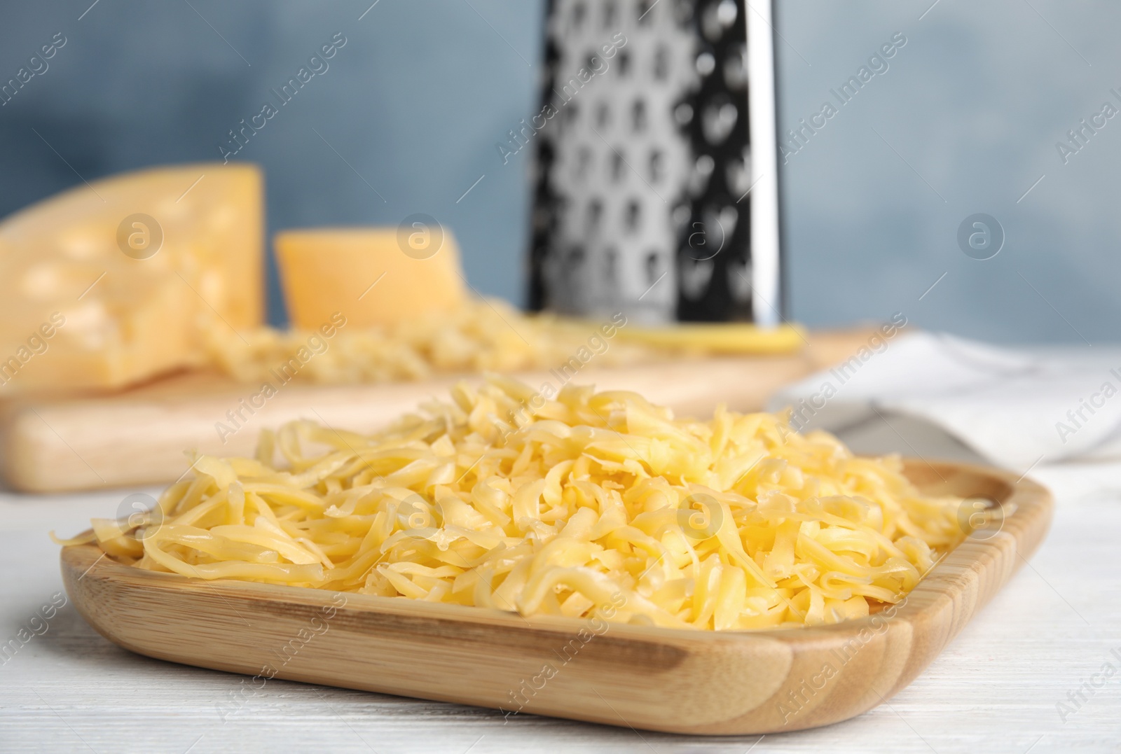 Photo of Delicious grated cheese on white wooden table, closeup