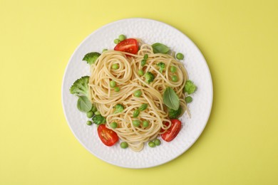 Photo of Plate of delicious pasta primavera on yellow background, top view