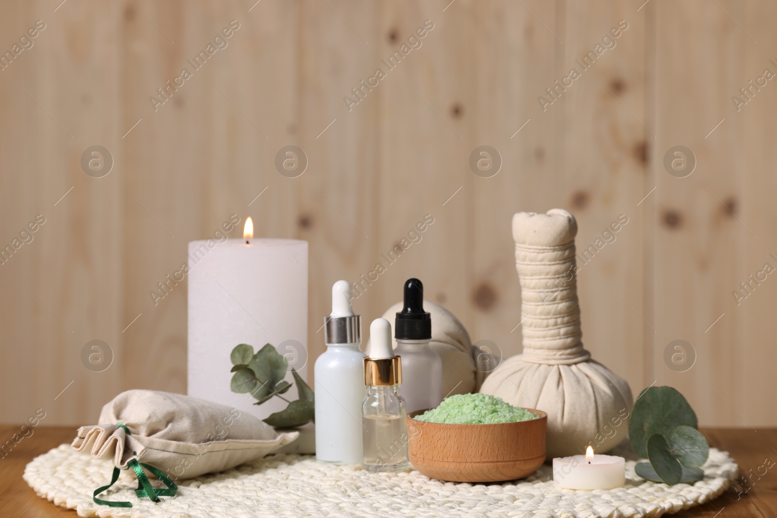 Photo of Different aromatherapy products, burning candles and eucalyptus leaves on table