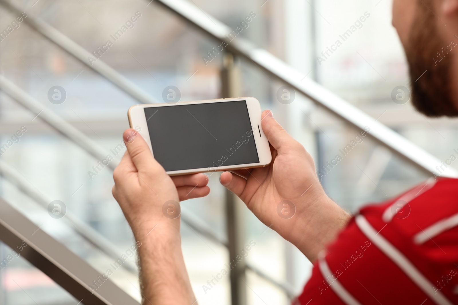 Photo of Young man using video chat on smartphone indoors, closeup. Space for design