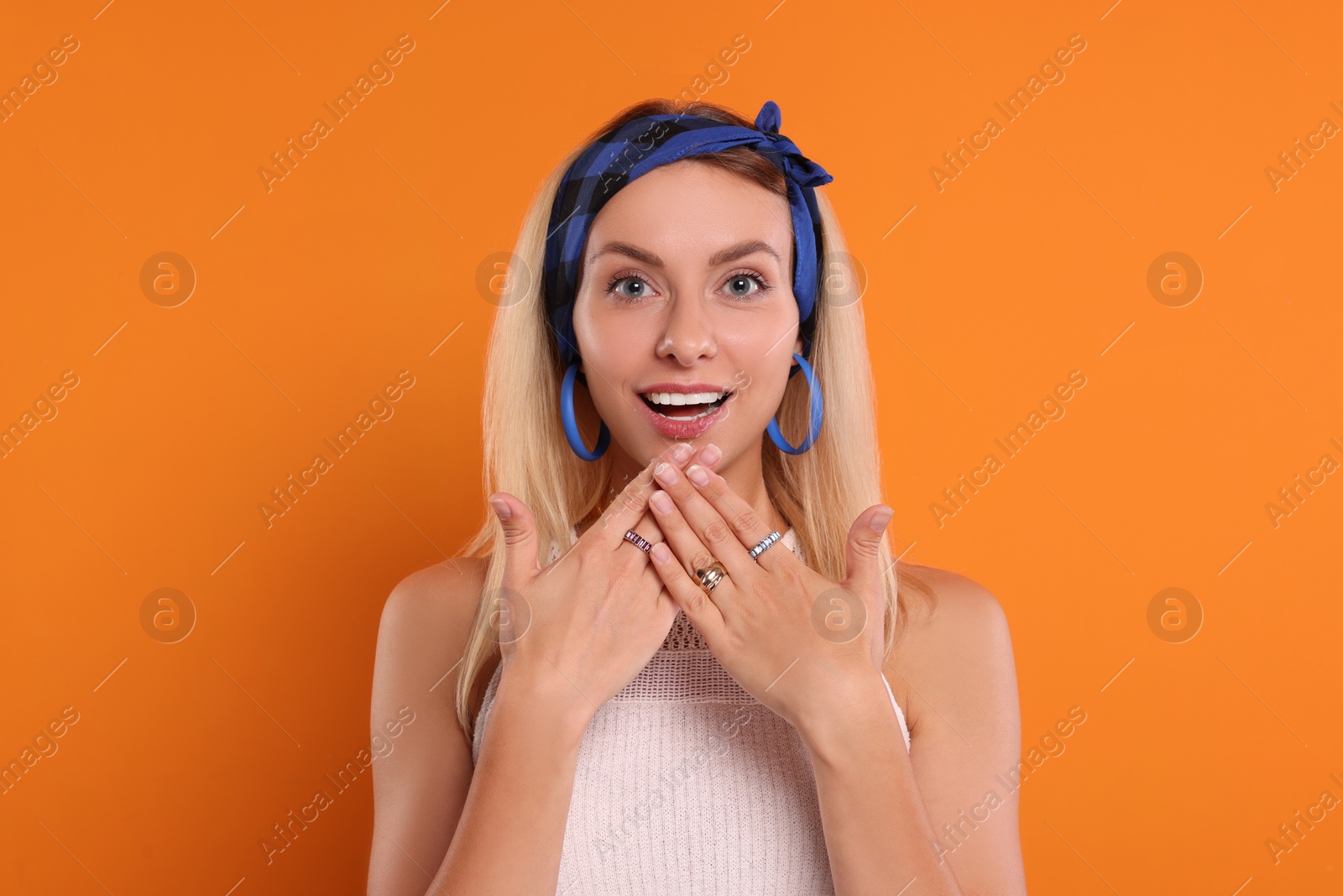 Photo of Portrait of surprised hippie woman on orange background