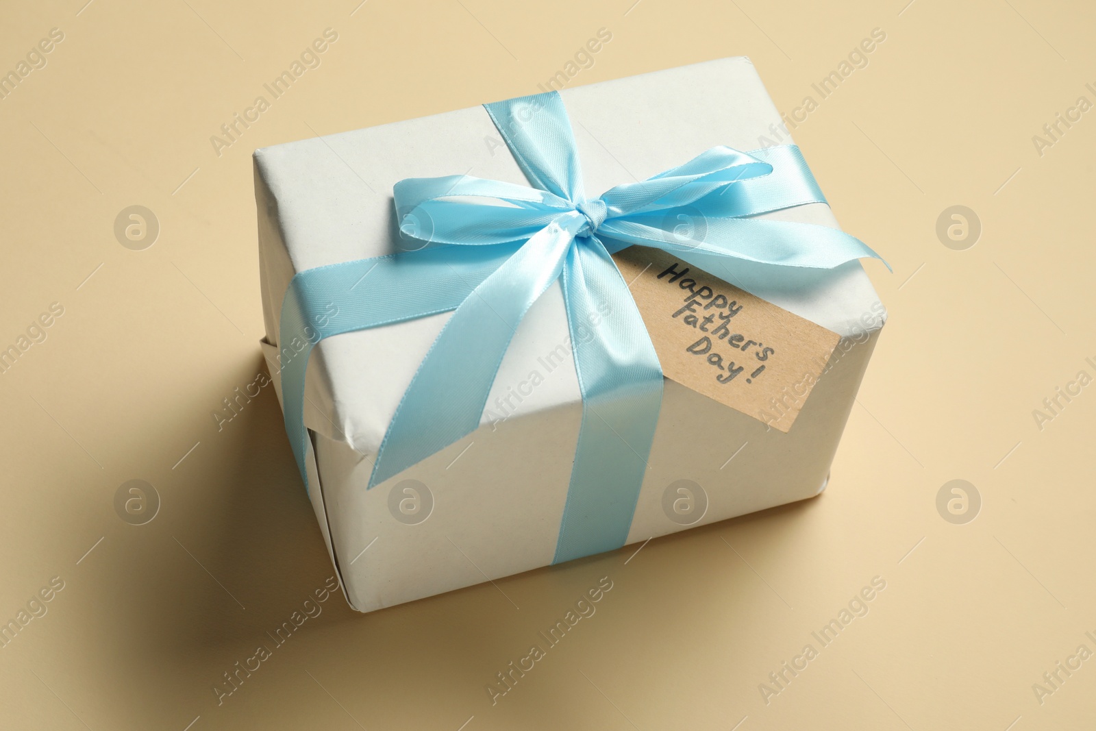 Photo of Card with phrase Happy Father's Day and gift box on beige background