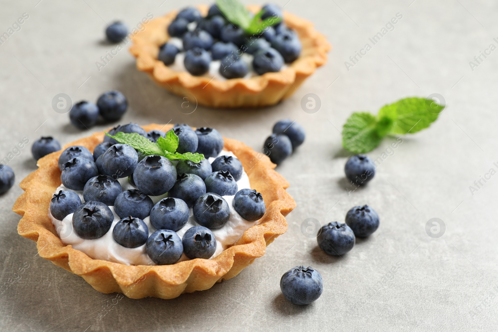 Photo of Delicious sweet pastry with berries on grey table. Space for text