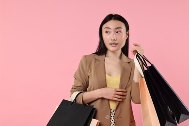 Photo of Beautiful woman with shopping bags on pink background. Space for text