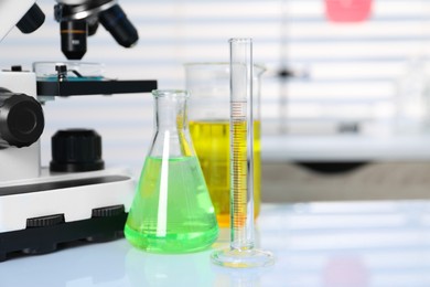 Photo of Laboratory analysis. Different glassware with liquids and microscope on white table indoors