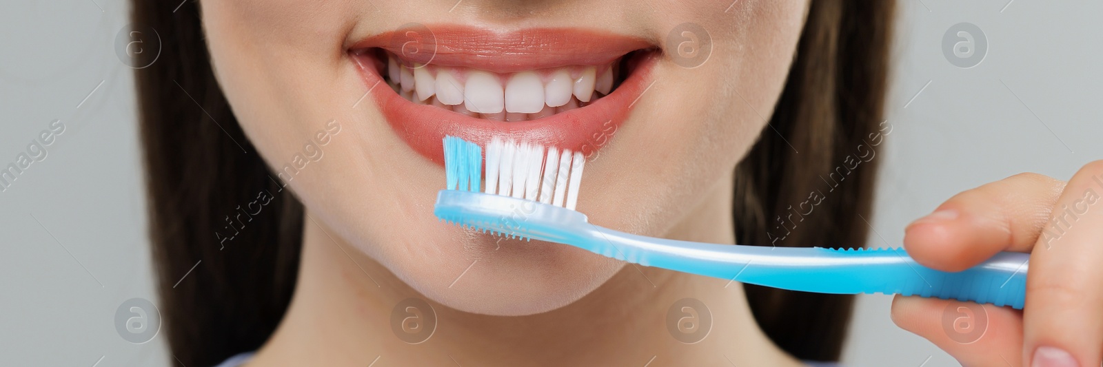 Image of Woman brushing her teeth with plastic toothbrush on light grey background, closeup. Banner design