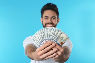 Photo of Happy young man with money on color background