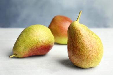 Photo of Ripe juicy pears on white wooden table against blue background