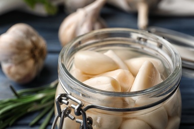 Photo of Preserved garlic in glass jar on table, closeup