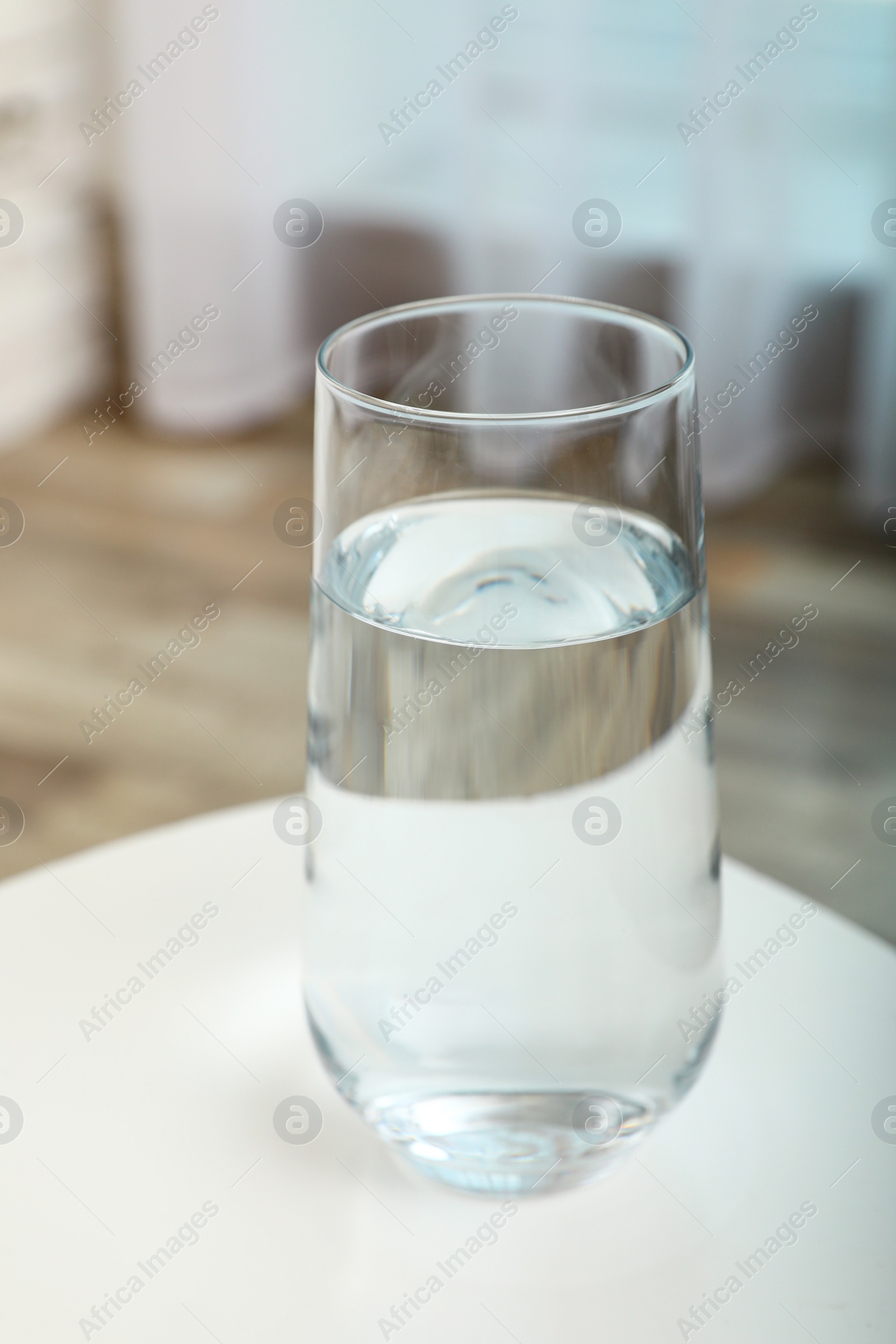 Photo of Glass of water on table in room. Refreshing drink