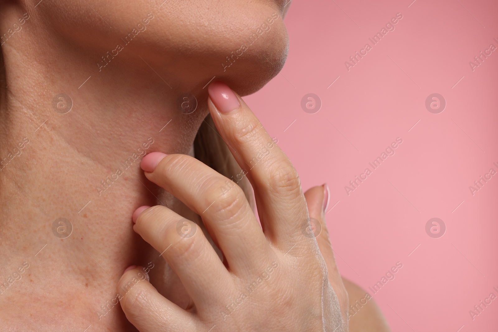 Photo of Woman touching her neck on pink background, closeup