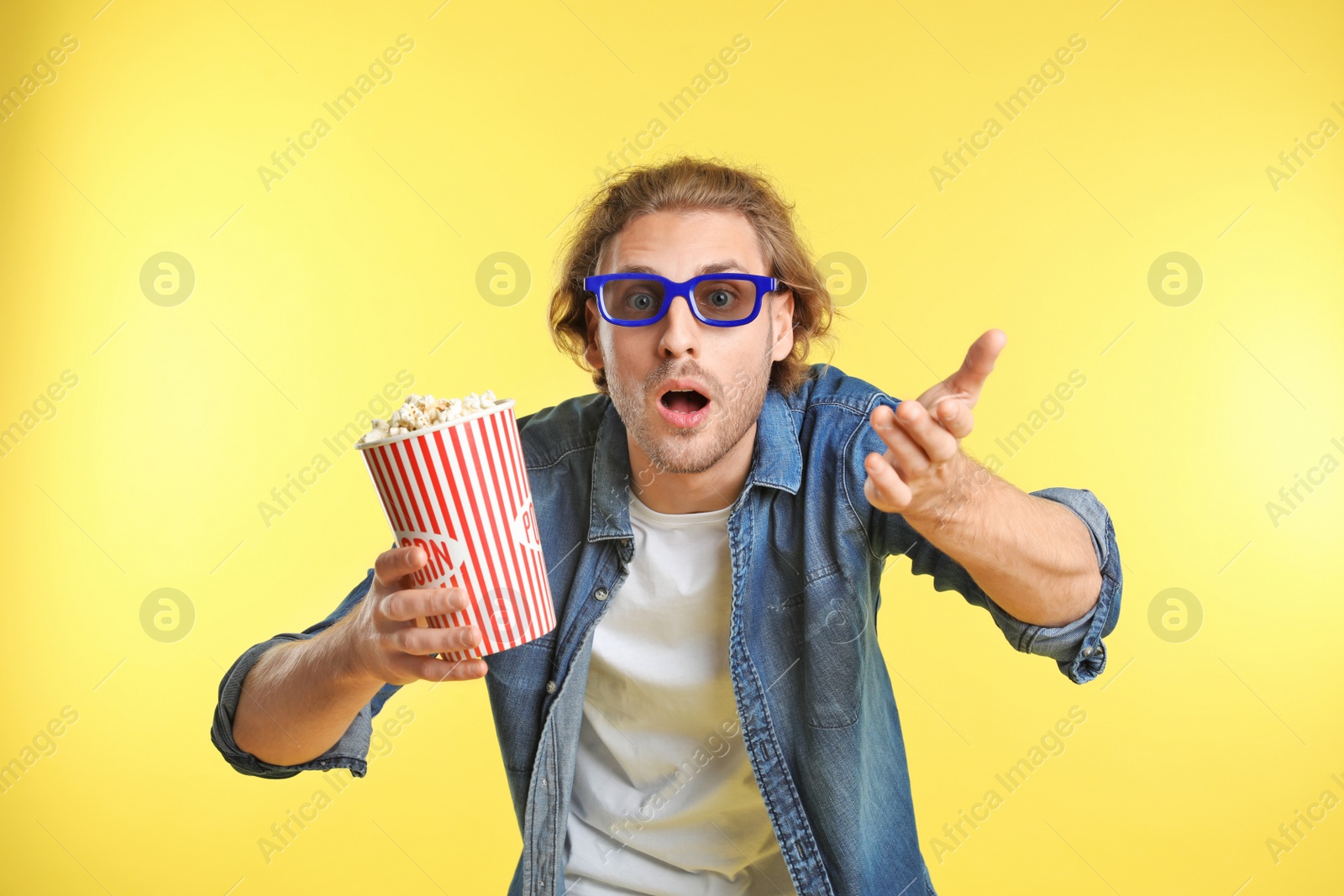 Photo of Emotional man with 3D glasses and popcorn during cinema show on color background