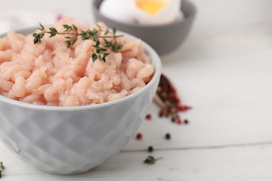 Fresh raw minced meat and thyme in bowl on white wooden table, closeup. Space for text
