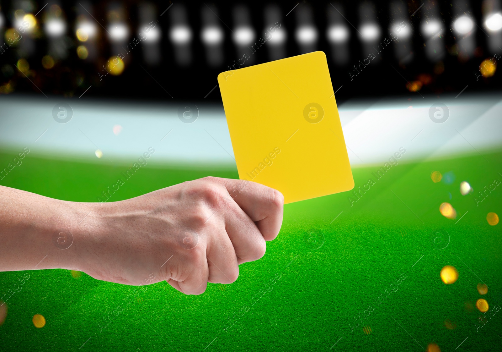 Image of Referee holding yellow card at stadium, closeup