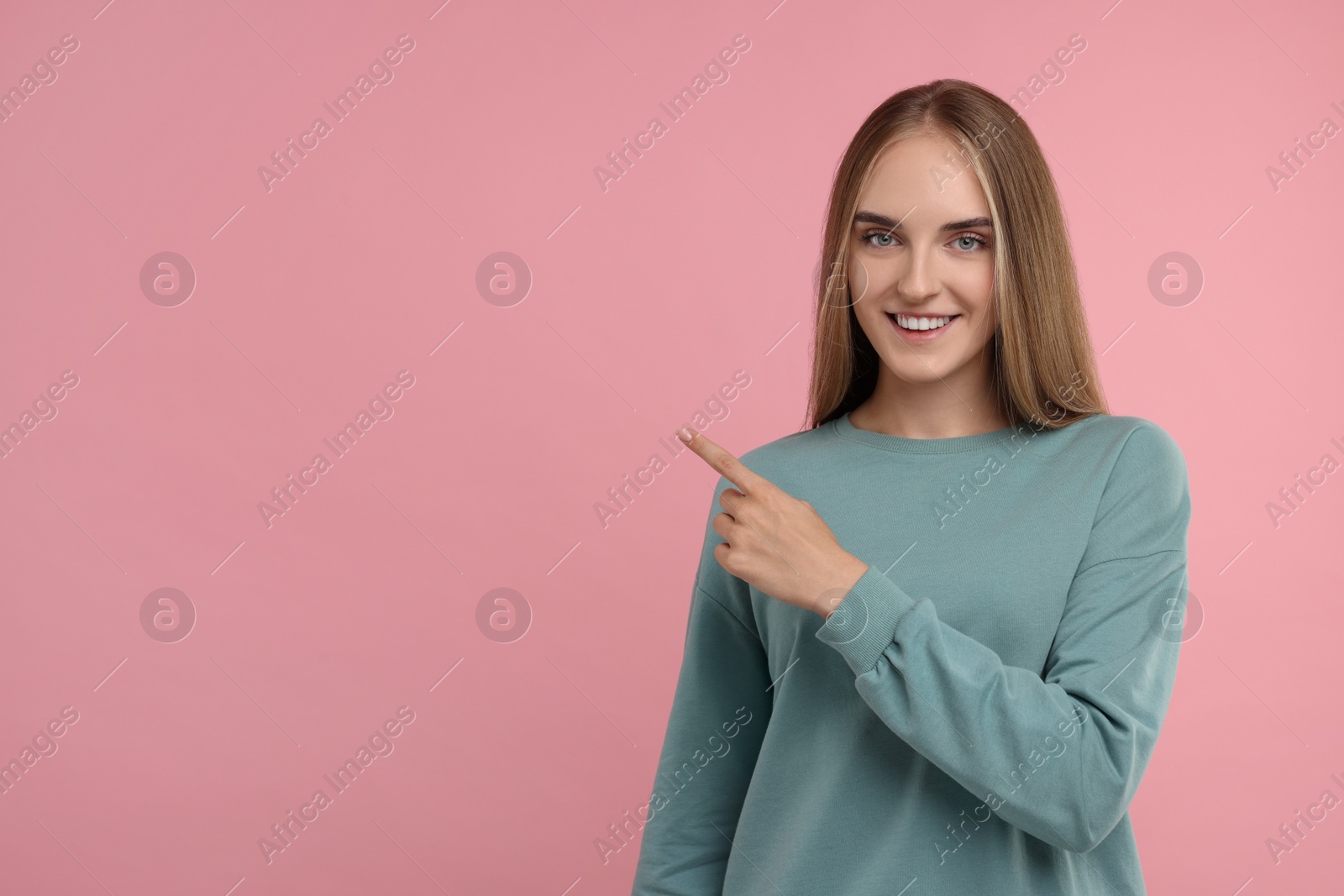 Photo of Special promotion. Happy woman pointing at something on pink background, space for text