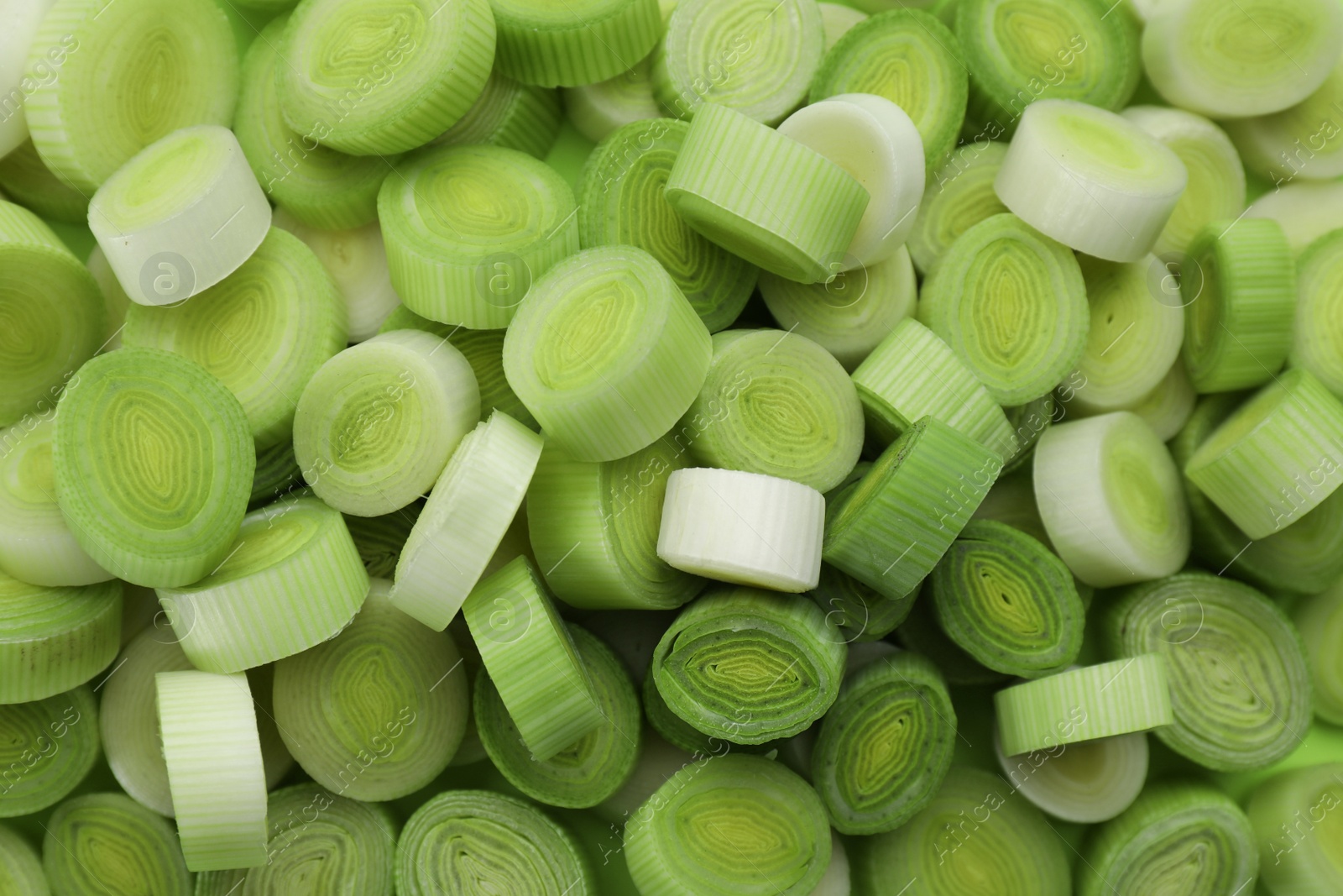 Photo of Fresh raw leek slices as background, top view